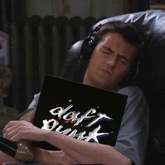 a man laying in a chair holding a book