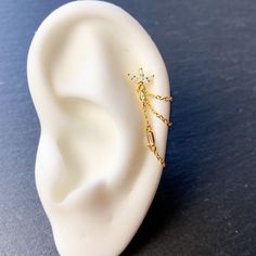 a pair of ear piercings sitting on top of a white plastic headpiece with gold chains