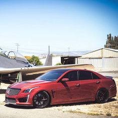 a red car parked next to an airplane