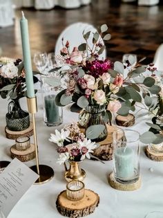 a table topped with vases filled with flowers and candles