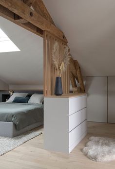 an attic bedroom with a bed, dresser and storage unit in the corner next to it