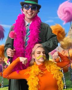 a man and woman with fake mustaches standing in front of some colorful decorations on the grass