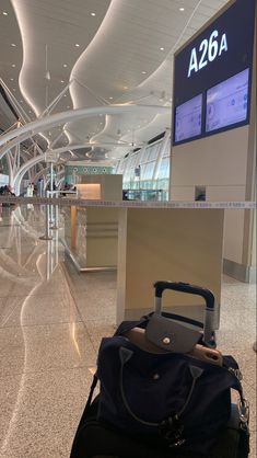 luggage sitting on the ground in an airport terminal with a large screen above it that says az66a