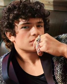 a young man with curly hair wearing a ring