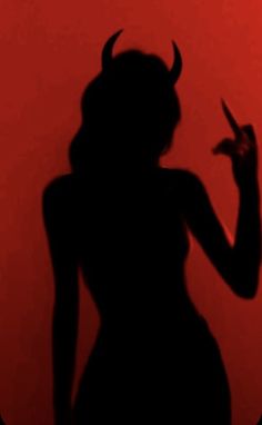 the silhouette of a woman with horns on her head and hands up in front of a red background