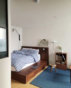 a bed sitting on top of a wooden platform next to a blue rug in a bedroom