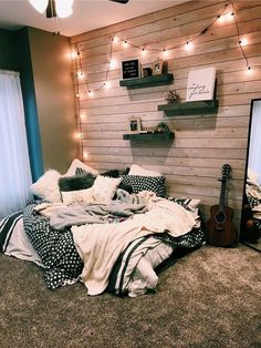 a bedroom with a guitar on the floor and lights strung from the wall above it