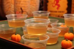 several plastic cups filled with liquid and small pumpkins