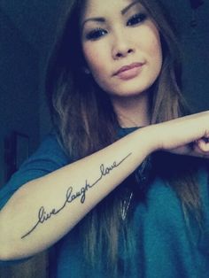 a woman with a tattoo on her arm that says live laugh love in cursive writing