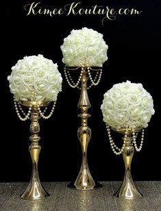 three gold vases with white flowers and pearls on them are sitting next to each other