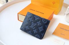 a louis vuitton wallet sitting on top of a table next to an orange box