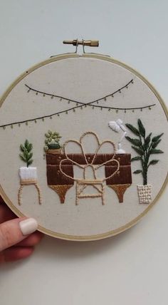 a hand is holding up a embroidery hoop with an image of a table and chairs on it