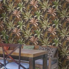 a wooden table sitting next to a brown wallpaper covered in green and red leaves