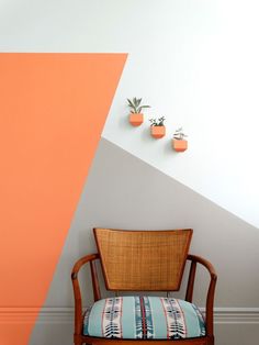 a chair sitting in front of a wall with two potted plants on top of it