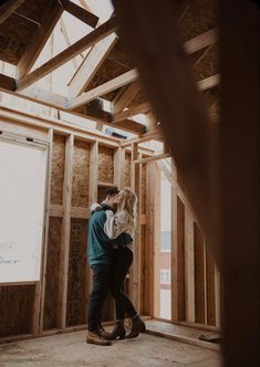 a man and woman hug in the middle of a room with wood framing around them