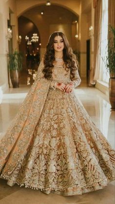 a woman in a gold and white wedding gown with long hair wearing a large veil