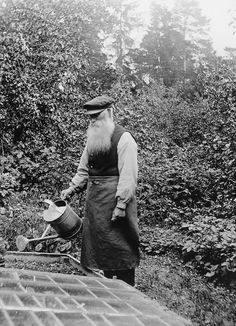 an old black and white photo of a man with a long beard holding a watering can