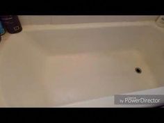 a white bath tub sitting on top of a bathroom floor next to a bottle of cleaner