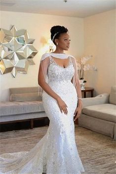 a woman in a white wedding dress standing in front of a living room with couches