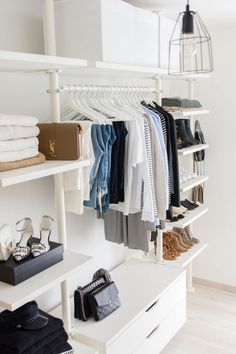 an organized closet with clothes, shoes and handbags on shelving units in white