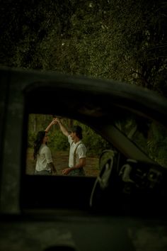 a man and woman standing next to each other in the back of a car at night