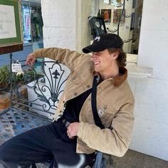 a smiling man sitting on a bench in front of a building with an iron gate