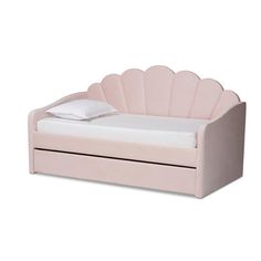 a pink daybed with a white pillow and pillows on it's back end