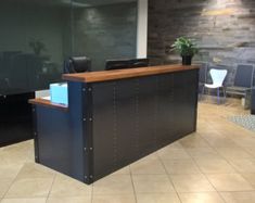 an office with a desk and chairs in front of a glass wall that has a plant on it