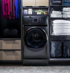 a washer and dryer in a closet with clothes hanging on the shelves next to it