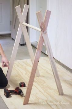 a person kneeling down on the floor working on some wooden structures with tools in front of them