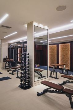 a gym with rows of exercise equipment and mirrors on the wall, along with benches