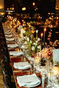 a long table is set with candles, flowers and napkins for an elegant dinner