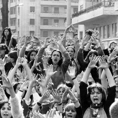 an old black and white photo of many people with their hands up in the air