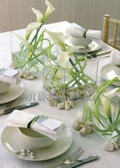 the table is set with white dishes and place settings