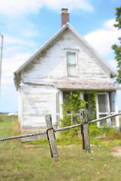 an old white house is behind a barbed wire fence with two wooden crosses on it