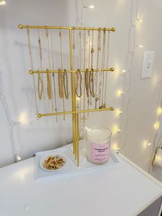 a gold jewelry stand with several necklaces on it and a bowl of food next to it