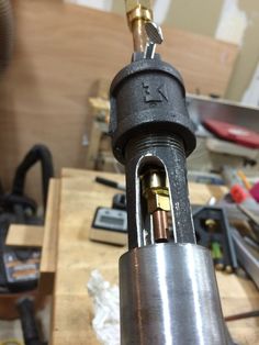 a close up of a metal object on a workbench with tools in the background