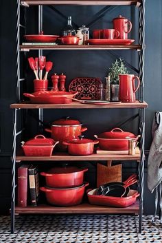 red pots and pans are stacked on shelves