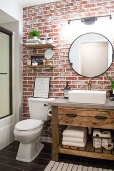 a white toilet sitting next to a bathroom sink under a mirror on top of a wooden cabinet