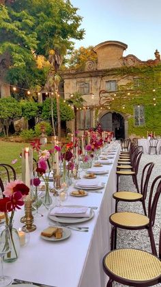 a long table is set up with flowers and candles for an outdoor wedding reception in the garden