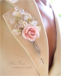 a boutonniere with a pink rose and pearls attached to the lapel