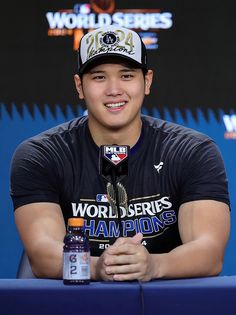 a young man sitting at a table with a bottle in front of him and smiling