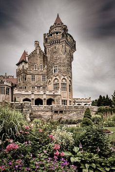 an old castle is surrounded by flowers and greenery