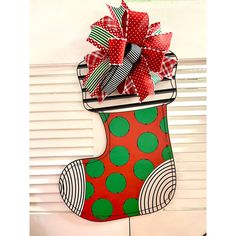 a christmas stocking decorated with red and green polka dot ribbon hanging on a wall