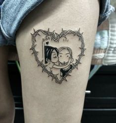 a couple in a heart shaped frame tattoo on the thigh with barbed wire around it