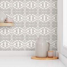 two white vases sitting on top of a counter in front of a wallpaper