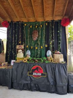 a table topped with cakes and desserts under a wooden structure covered in black tarp