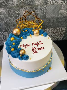 a white cake with blue and gold decorations on it's side sitting on a plate