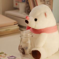 a white stuffed bear sitting next to a jar