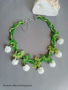 a green and white beaded bracelet with flowers on it next to a rock ornament